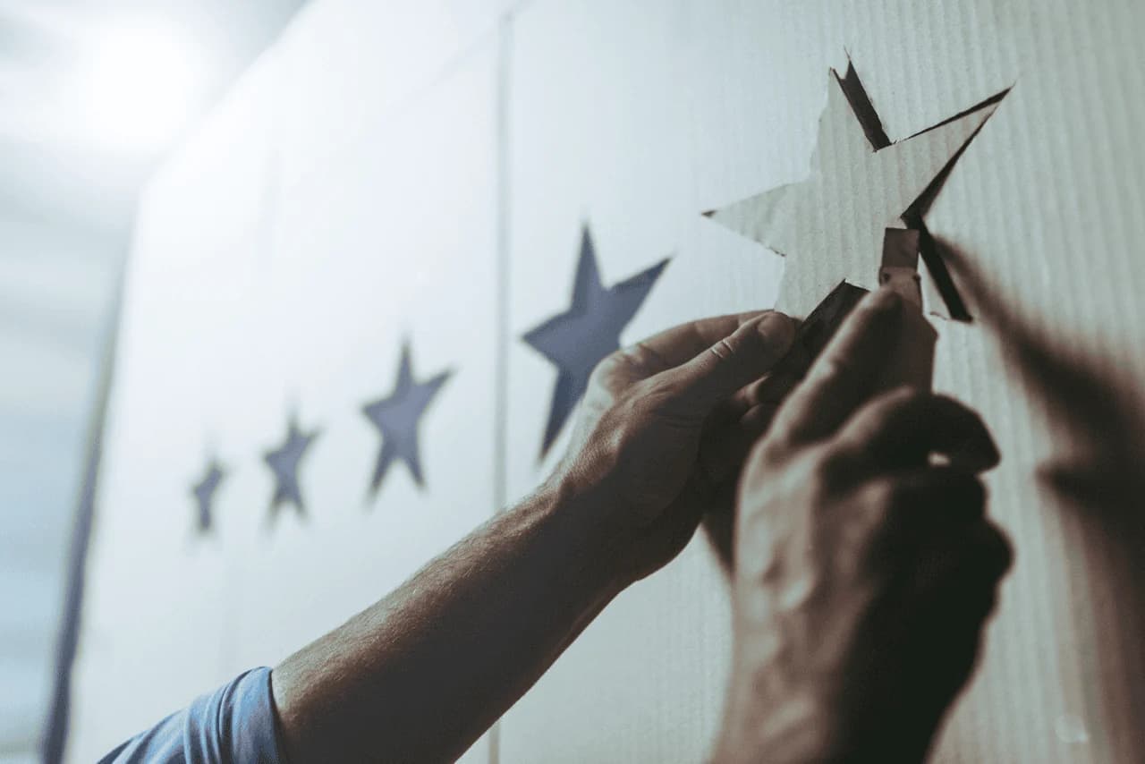Hands drawing five stars on a board